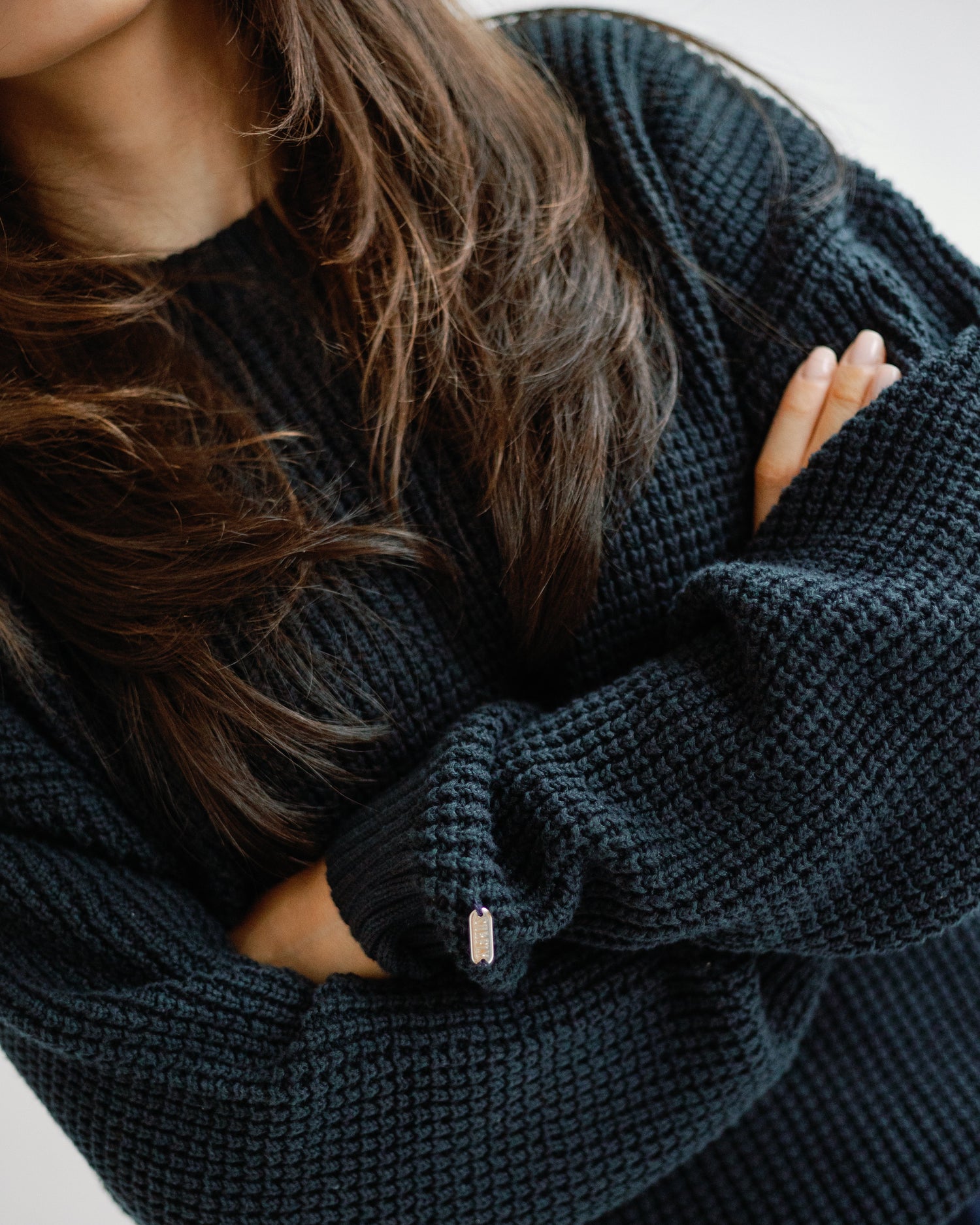 Person wearing a dark navy knitted sweater with a blurred background